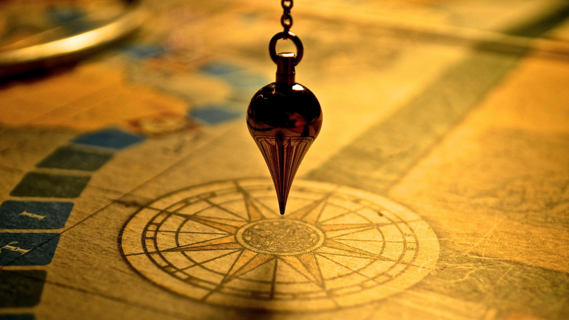 A pendulum hanging above a compass rose drawn on an old map.